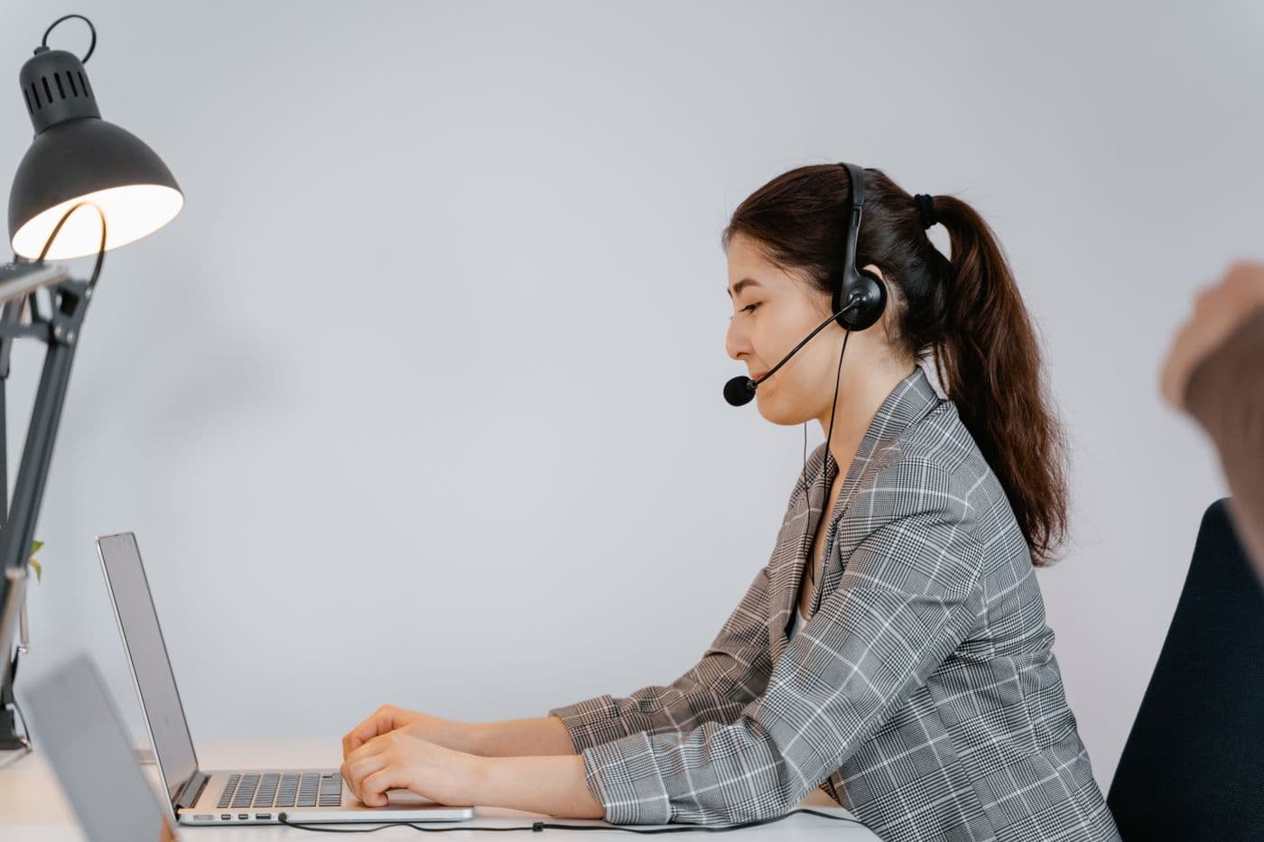 A remote professional with a headset working on her laptop