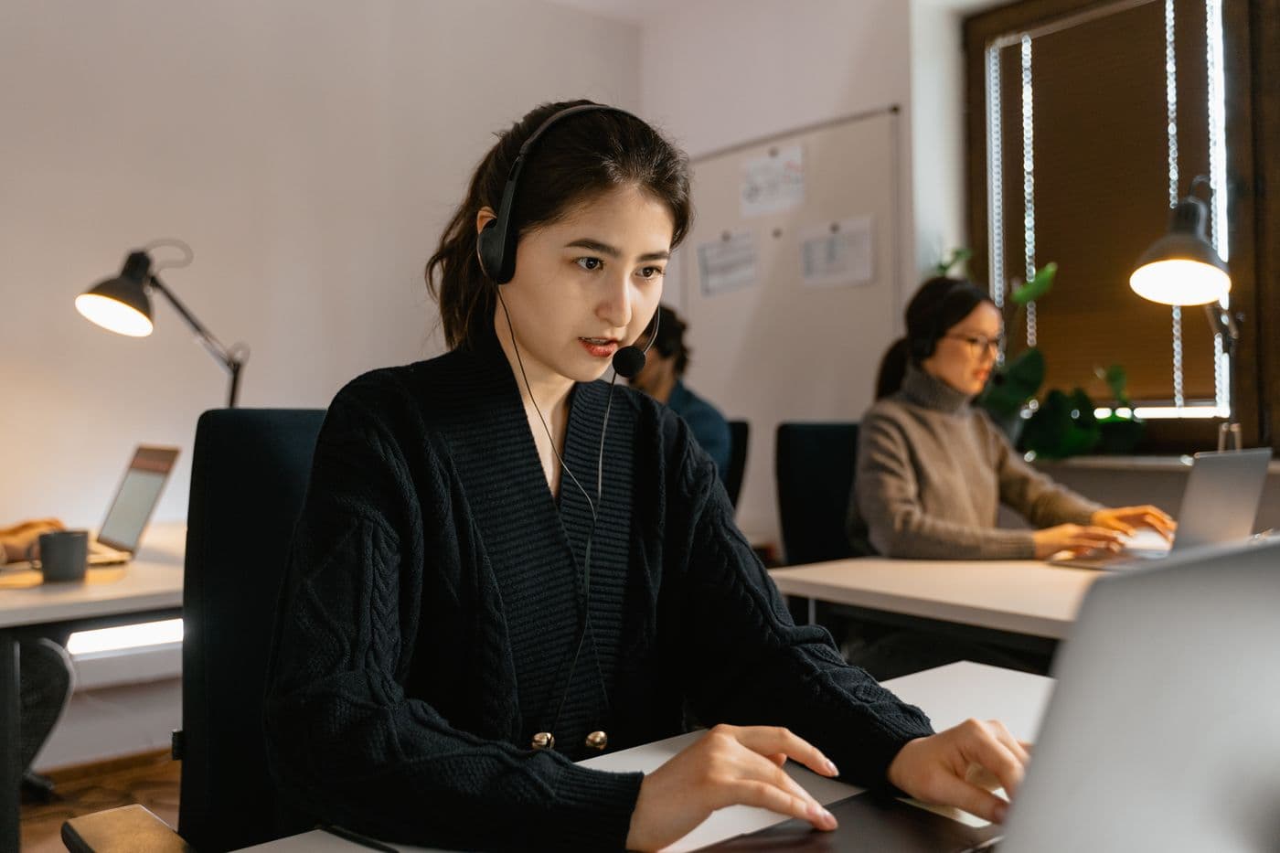 A support professional wearing a headset, working at her laptop